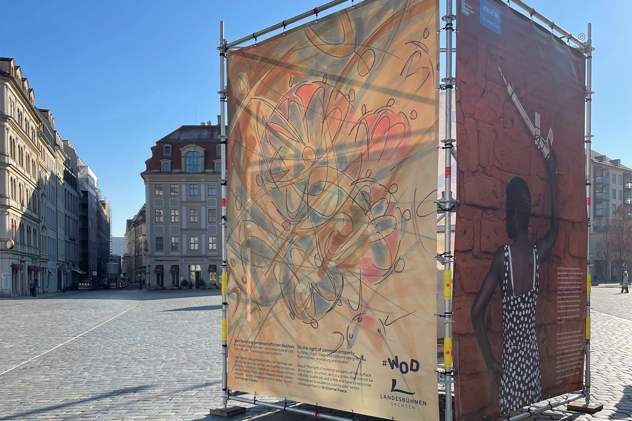 Auf einem kopfsteingepflasterten Platz in Dresden stehen Bauzäune mit einer Plakataktion zum Thema "Weltoffenes Dresden".